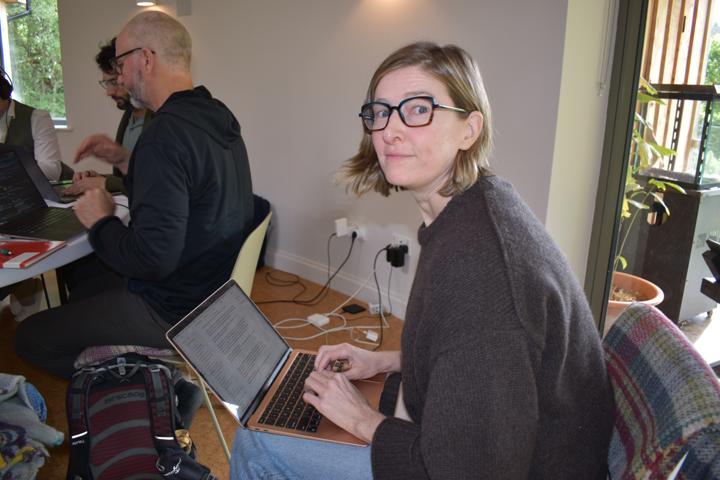 A person at a laptop glancing up towards the camera.