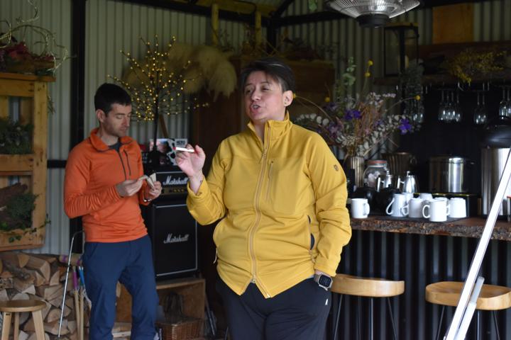 Two people presenting side by side in front of the shed's bar.