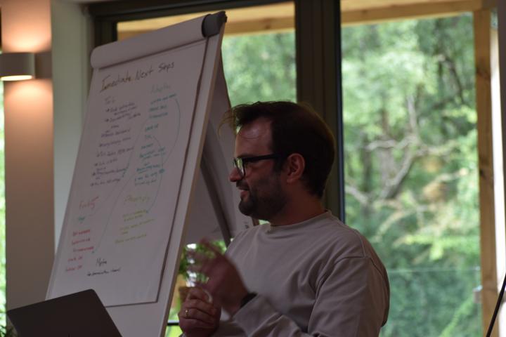 A person beside a flip chart headed Immediate Next Steps.